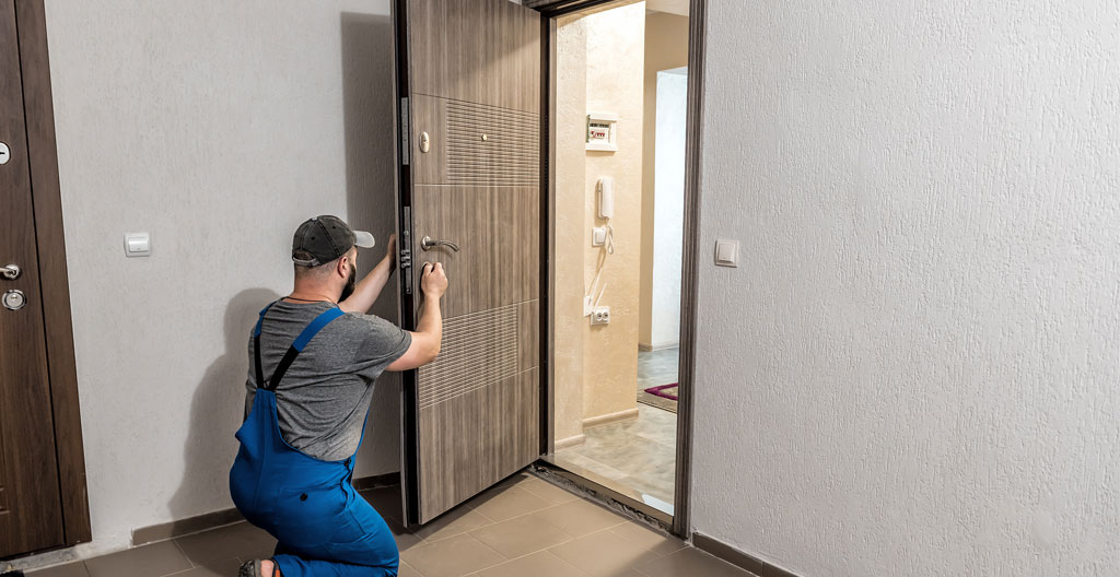 Technicien installant professionnellement une porte extérieure avec outils spécialisés sur chantier résidentiel